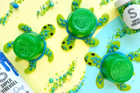 Drei grüne Wackelpudding-Schildkröten mit Streuseln und einem Drip-Fläschchen. Lustige Wackelpudding-Ideen für den Sommer.