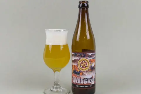 Szklanka z bursztynowym piwem i pianką obok butelki "Misty" Contemporary IPA. Idealny new england ipa na wieczór.