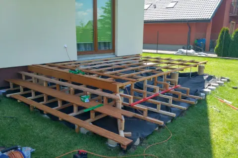 Budowa tarasu na słupach betonowych. Drewniana konstrukcja czeka na deski.