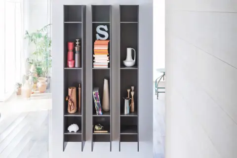 Scaffali grigi con oggetti decorativi, piante e libri, che creano un effetto camino ventilazione naturale.