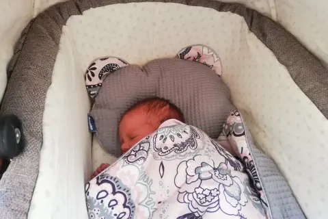 Śpiące niemowlę w wózku, otulone kolorowym kocykiem. Zastanawiasz się, jak długo spacerować z niemowlakiem zimą?