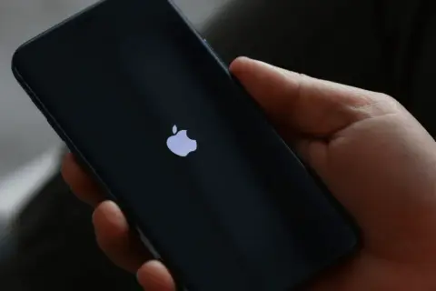 Dłoń trzyma iPhone 13 z logo Apple. Czas na reset? Dowiedz się, jak zresetować iPhone 13.