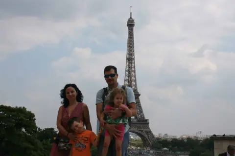 Famille souriante devant la Tour Eiffel, un classique des choses à faire à Paris avec des enfants.