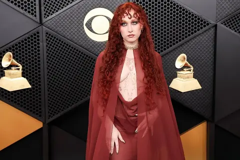 Chappell Roan, con su cabello rojo rizado y un atuendo transparente, posa en la alfombra de los Grammy.