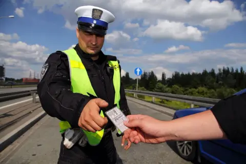 Policjant w kamizelce odblaskowej prosi o okazanie dokumentów. Czy trzeba mieć przy sobie prawo jazdy? Tak, podczas kontroli drogowej.