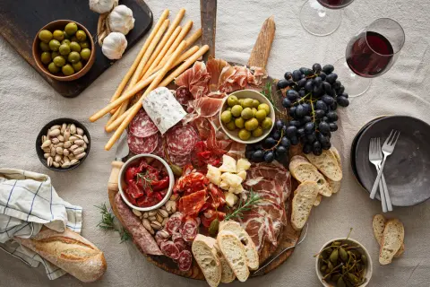 En generös bricka med italienska snacks: charkuterier, oliver, soltorkade tomater, ost, vindruvor, grissini och bröd. Perfekt för en mysig kväll.