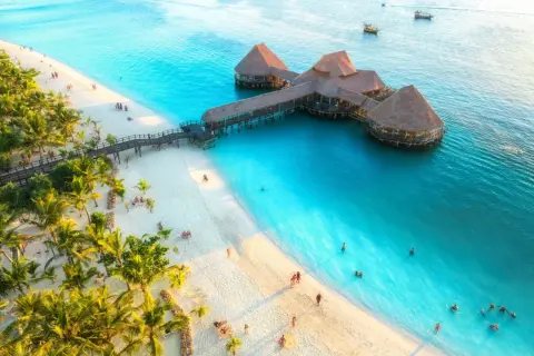 Rajska plaża na Zanzibarze z palmami i restauracją na wodzie. Sprawdź zanzibar ceny i zaplanuj wymarzone wakacje!