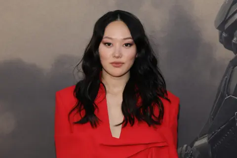 Yerin Ha, con su cabello oscuro y un elegante traje rojo, posa con confianza.