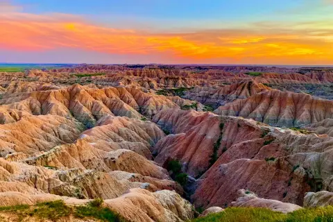 Paisaje de **las carcavas** erosionadas bajo un cielo anaranjado y azul al atardecer.
