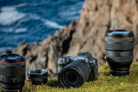 Canon EOS R camera with RF 50mm, RF 24-105mm lenses, and mount adapter on grass.