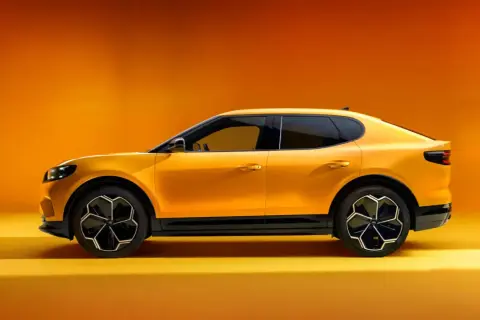 Żółty Ford Capri 2025, sportowy SUV z futurystycznym designem, prezentuje się na tle pomarańczowego gradientu.