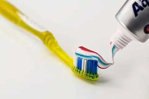 Szczoteczka z kolorową pastą, na której widać strumień z tubki. Czy fluor jest szkodliwy? Debata trwa, ale pasta z fluorem chroni zęby.