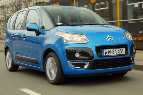 Niebieski Citroen C3 Picasso 2009 jedzie ulicą, mijając tramwaj.