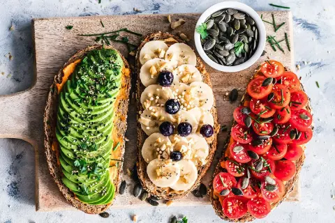 Trois toasts variés : avocat, banane-myrtille, tomates. Une alimentation riche en protéines pour bien commencer la journée.