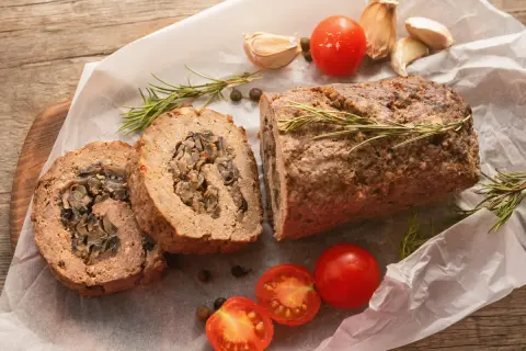 Pyszna rolada z mięsa mielonego z grzybami, podana z pomidorkami i rozmarynem.