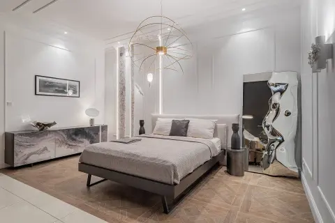 Nowoczesna sypialnia z łóżkiem, marmurową komodą i designerskim lustrem. Inspiracja, jak urządzić sypialnię w eleganckim stylu.