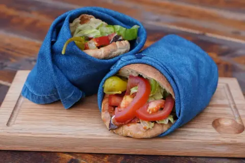 Två kebabrullar med färska grönsaker, inlindade i jeans, serverade på en träbricka. Ett enkelt och gott kebab recept.