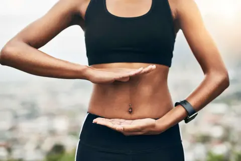 Femme pratiquant des exercices abdo hypopressifs, mains posées sur son ventre plat.