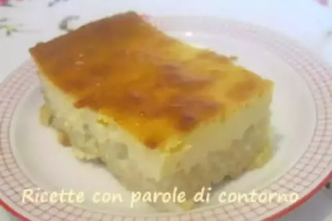 Una fetta di torta di riso carrarina, con una base soffice e una crema dorata in superficie, servita su un piatto a scacchi.