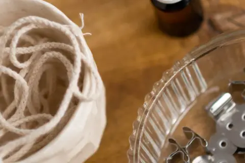 Bawełniany sznurek w ceramicznym naczyniu i metalowe stopki do knotów – idealne, by dowiedzieć się, z czego zrobić knot do świeczki.