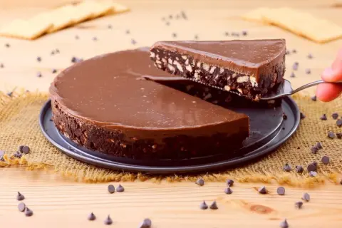 Torta al cioccolato con biscotti, un'idea per dolci velocissimi senza cottura. Una fetta viene sollevata con una paletta.