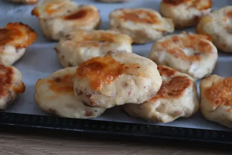 Polpette al forno dorate e invitanti, con formaggio fuso e pezzetti di carne visibili nell'impasto.
