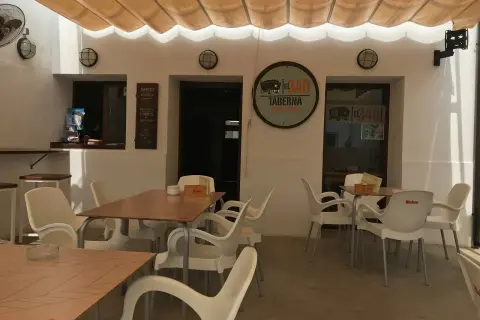 Terraza del restaurante 340, con mesas y sillas de plástico blanco bajo un toldo beige.
