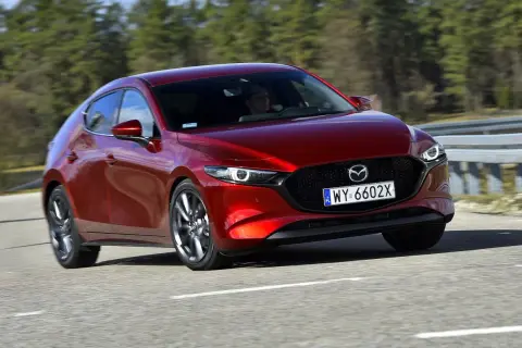 Czerwona Mazda 3 2025 na drodze, z widocznym kierowcą.