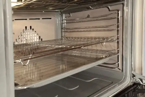Wnętrze piekarnika z rusztami i blachą, gotowe do czyszczenia katalitycznego.