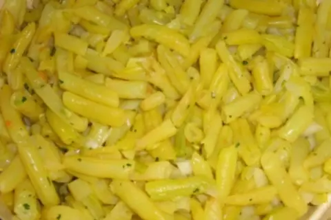 Nahaufnahme von gekochten gelben Bohnen, gewürzt mit Kräutern und Zwiebeln. Ein leckeres Gericht mit gelben Bohnen.