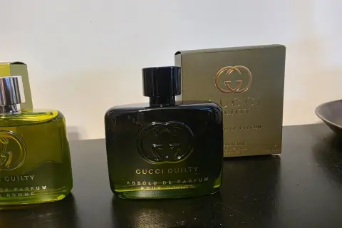 Dwie butelki perfum Gucci Guilty na ciemnym tle, jedna z nich z pudełkiem.