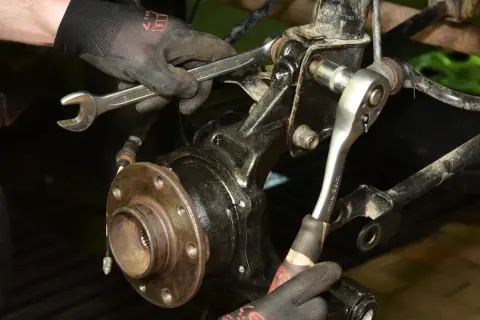 Mechanik dokręca śruby przy piaście, gdzie znajduje się łożysko w kole.
