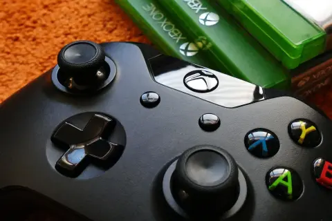 Czarny kontroler Xbox i zielone pudełka z grami. Idealny zestaw do wspólnej zabawy w gry survival multiplayer.