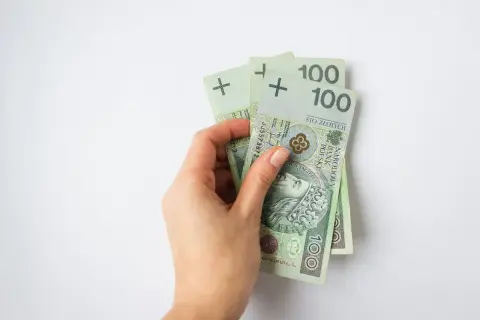 Dłoń trzyma trzy banknoty po 100 złotych. To dobry start do oszczędzania.
