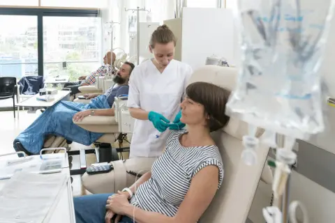 Eine Krankenschwester verbindet eine Patientin mit Infusion. Sie verträgt die chemo gut, ein gutes Zeichen.