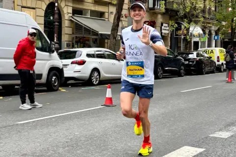 Nathan corre i 10 km in gara, salutando con la mano. Il tempo è ancora da definire, ma la sua energia è palpabile.