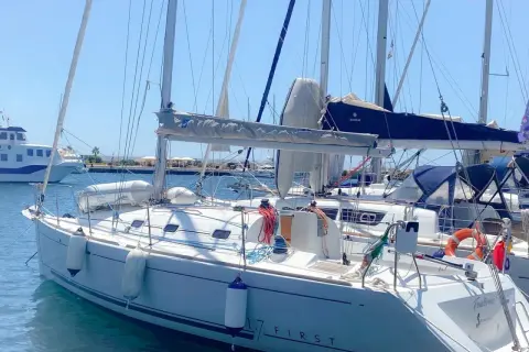 Barca a vela bianca ormeggiata, con scritte "17 FIRST" e "Finistère". Dettagli tecnici e mare calmo.