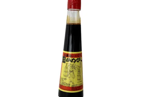 En flaska mörk sojasås med en röd kork. Etiketten visar en figur som bär korgar, vilket antyder att soja kan bli gammal och utveckla smak.