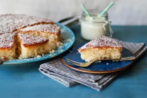 Deliziosa torta con farina di cocco, spolverata di zucchero a velo, servita su piatti blu.