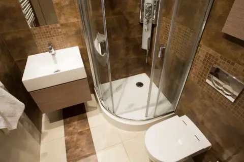 Salle de bain rouille et bois : douche d'angle, lavabo suspendu, toilettes. Ambiance chaleureuse et moderne.