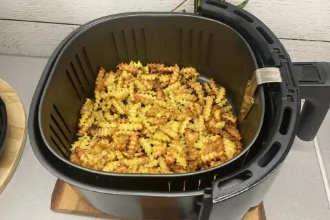 Chrupiące, pofalowane frytki ziemniaczane w koszu frytkownicy beztłuszczowej.