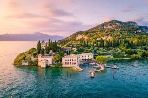 Un'isola incantevole sul gardasee westufer, con ville storiche, cipressi e ulivi, bagnata da acque turchesi al tramonto.