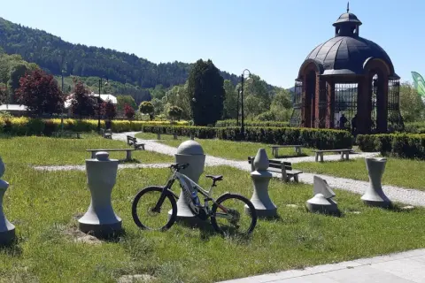 Rower czeka na przygodę na trasie w Muszynie, wśród kamiennych figur i zieleni.