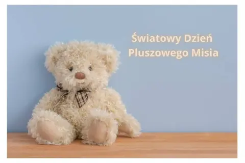 Jasny pluszowy miś z brązową kokardką na jasnoniebieskim tle.
