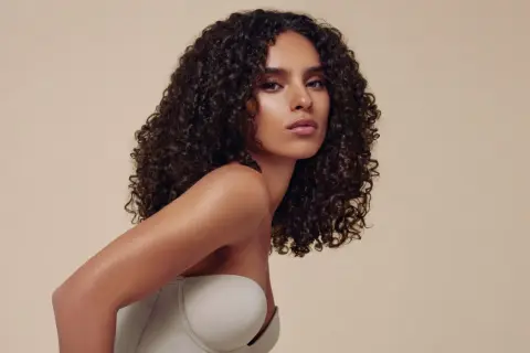 Descubre cómo peinar pelo rizado con esta modelo de cabello oscuro y voluminoso. Su melena luce definida y brillante, perfecta para cualquier ocasión.