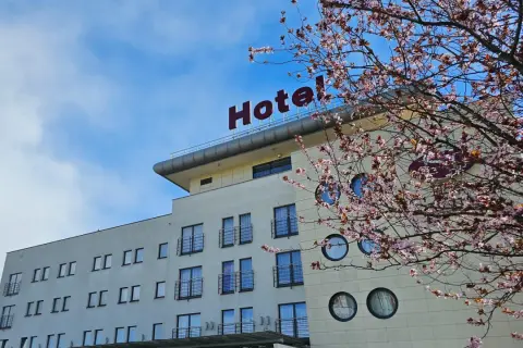 Nowe hotelowe opinie o hotelu z kwitnącą wiśnią w tle.