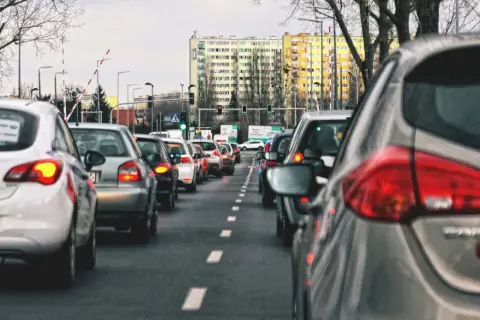 Korki miejskie, gdzie zasady jazdy samochodem po mieście wymagają cierpliwości. Długi rząd aut na drodze, budynki w tle.