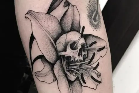 Tatuaże więzienne kropki: czaszka w lilii, symbolizująca przemijanie.