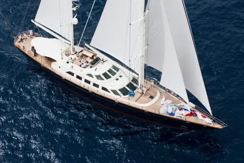 Lussuoso yacht a vela, forse il yacht Berlusconi, solca le acque blu con vele bianche spiegate.