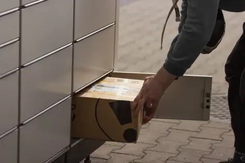 Osoba wkłada paczkę do paczkomatu InPost.